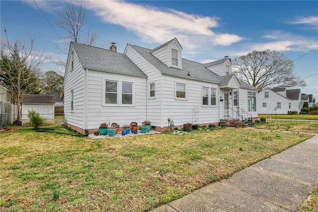 cape cod-style house featuring a front yard, fence, roof with shingles, and a chimney