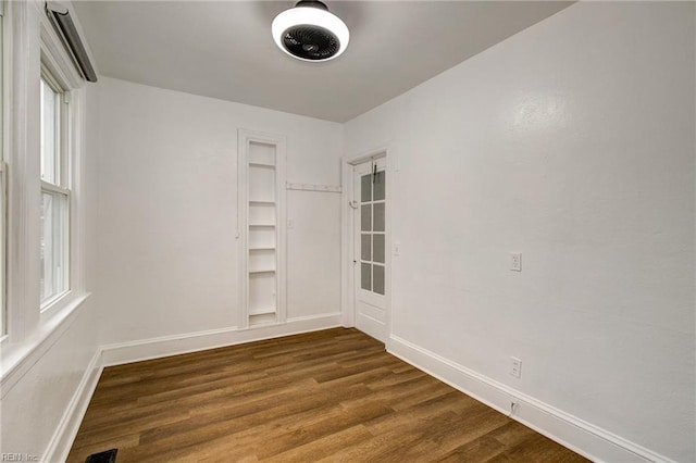 unfurnished room featuring a healthy amount of sunlight, dark wood-type flooring, and baseboards