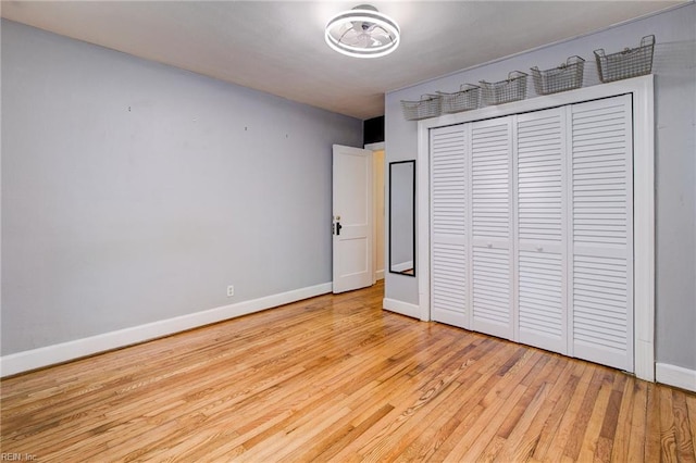 unfurnished bedroom featuring baseboards, light wood-type flooring, and a closet