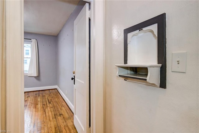 corridor with hardwood / wood-style floors and baseboards