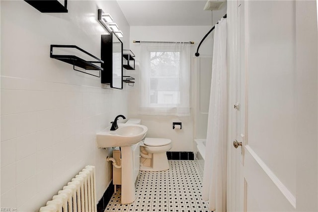 bathroom featuring toilet, radiator heating unit, shower / bath combination with curtain, tile walls, and a sink