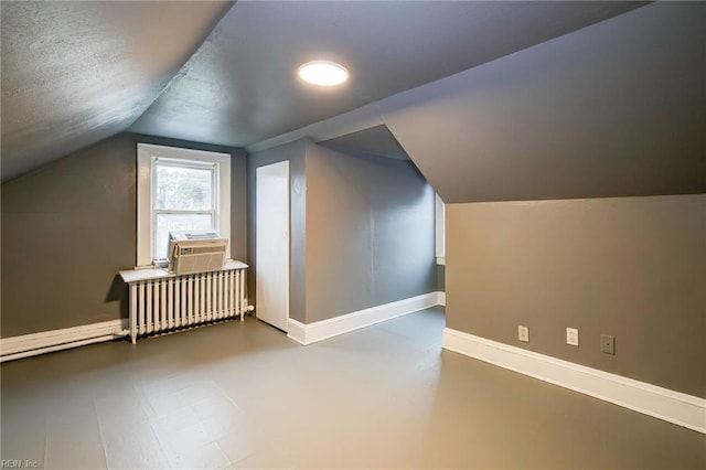 bonus room featuring radiator, baseboards, vaulted ceiling, cooling unit, and a textured ceiling