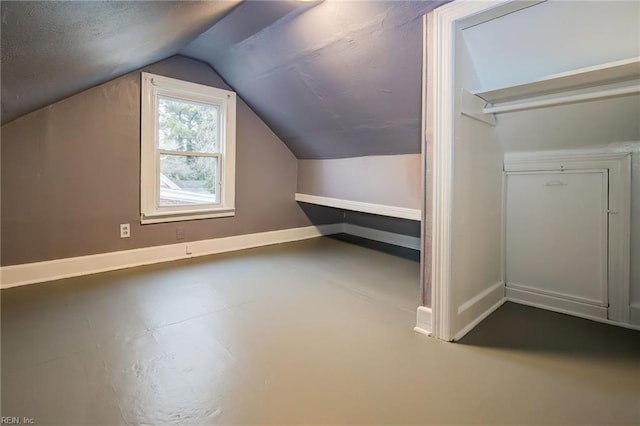 additional living space with vaulted ceiling, baseboards, and a textured ceiling