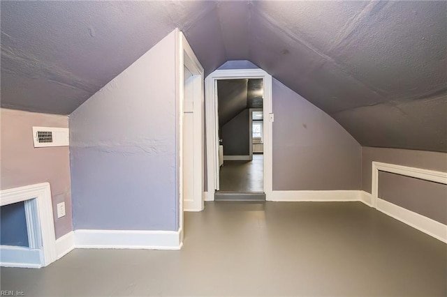 additional living space featuring vaulted ceiling, visible vents, baseboards, and a textured ceiling