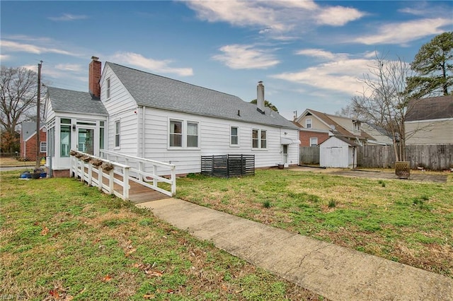 back of house with an outbuilding, fence, a chimney, a storage shed, and a lawn