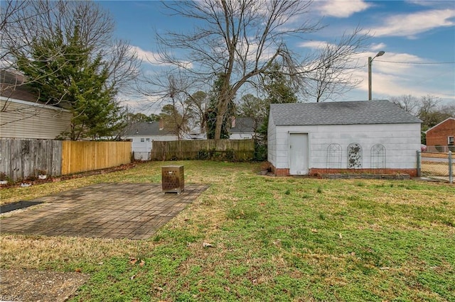 view of yard featuring an outdoor structure, a fenced backyard, and a patio area