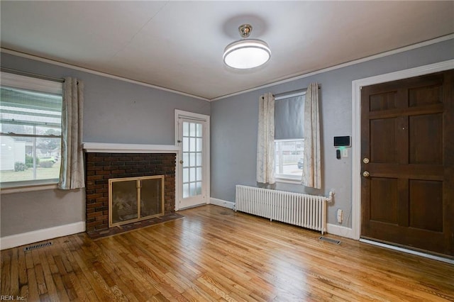 unfurnished living room featuring visible vents, radiator, crown molding, a fireplace, and hardwood / wood-style flooring