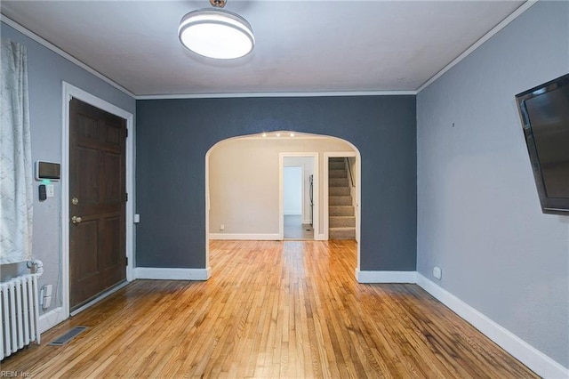 unfurnished room with visible vents, arched walkways, radiator, and crown molding