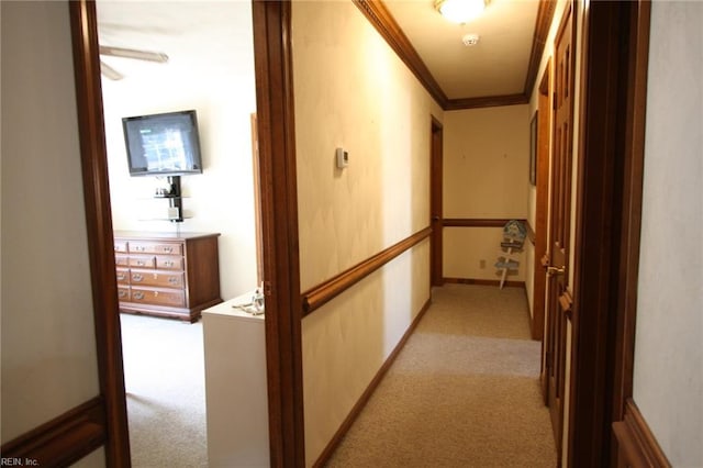 corridor with light colored carpet, baseboards, and ornamental molding