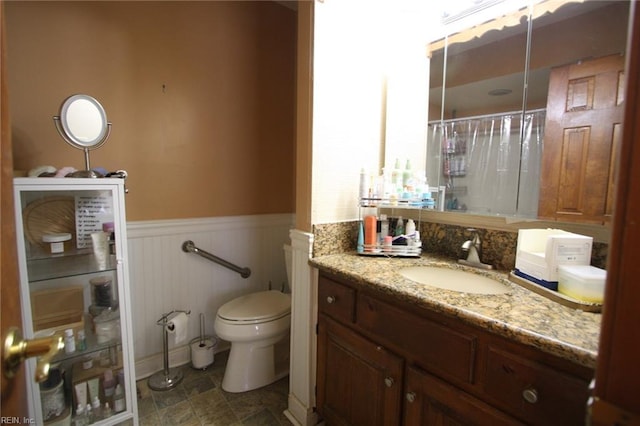 full bathroom featuring curtained shower, toilet, vanity, and wainscoting