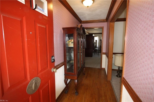 foyer entrance featuring baseboards, wood finished floors, ornamental molding, and wallpapered walls