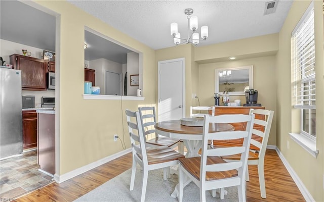 dining room featuring visible vents, an inviting chandelier, and light wood-style flooring