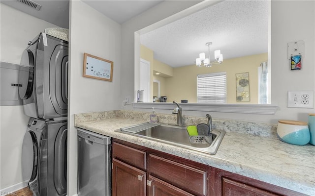 kitchen featuring visible vents, stacked washing maching and dryer, a sink, light countertops, and dishwasher