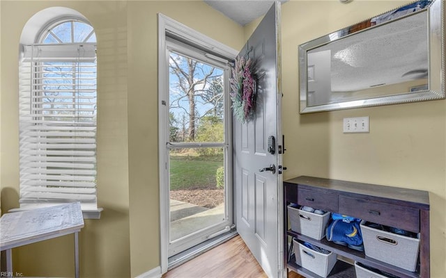 doorway with wood finished floors and baseboards