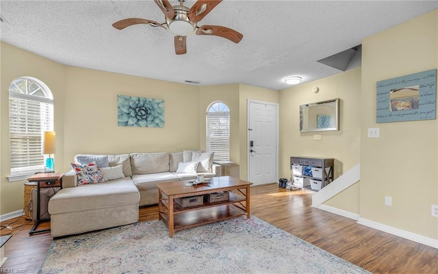 living room with visible vents, baseboards, ceiling fan, wood finished floors, and a textured ceiling