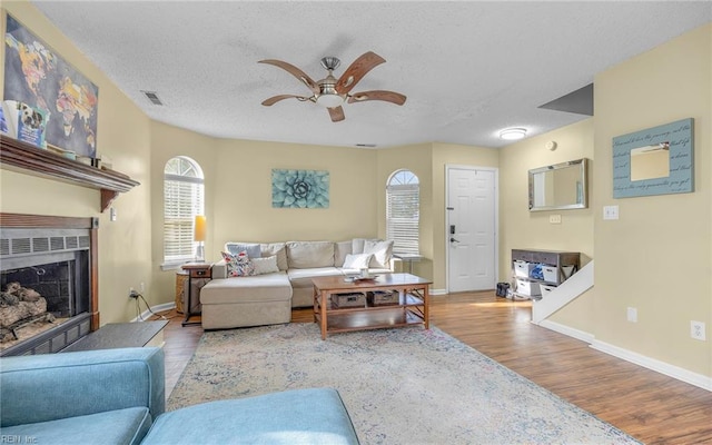 living area with visible vents, a fireplace, a textured ceiling, and wood finished floors