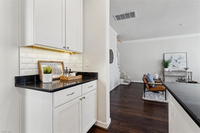 kitchen featuring tasteful backsplash, visible vents, dark wood-type flooring, ornamental molding, and white cabinets