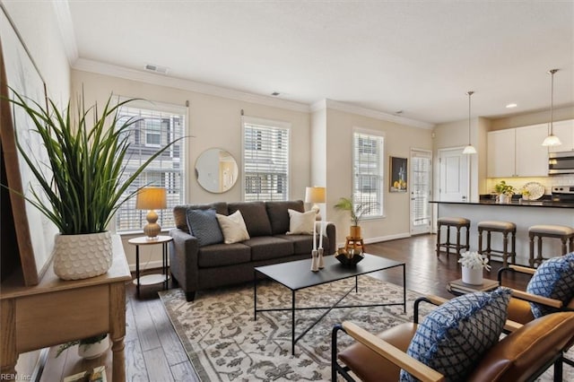 living area with visible vents, baseboards, dark wood-type flooring, and ornamental molding