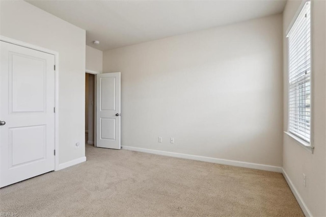 unfurnished bedroom with light colored carpet and baseboards