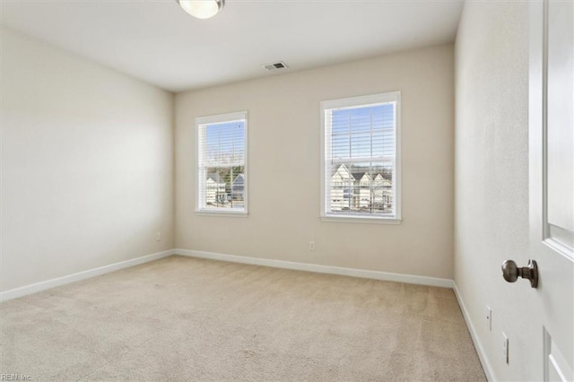 unfurnished room with baseboards, visible vents, and light carpet