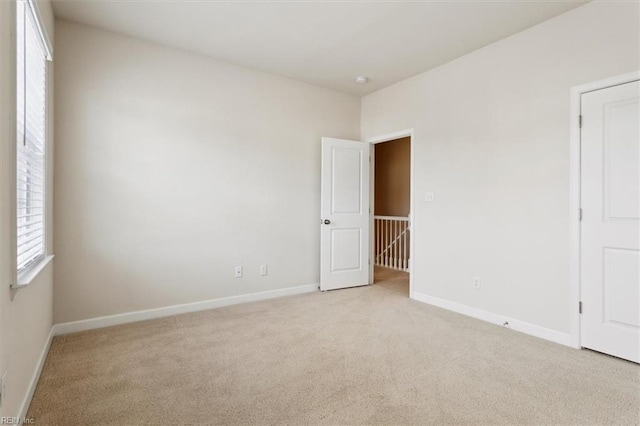 spare room with baseboards and light carpet