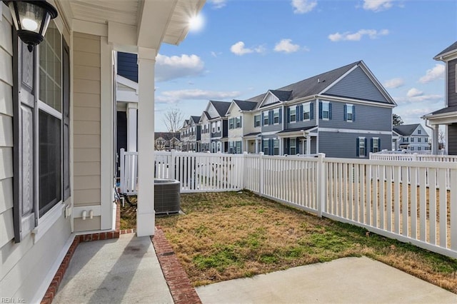 view of yard featuring a residential view, central AC unit, and a fenced backyard