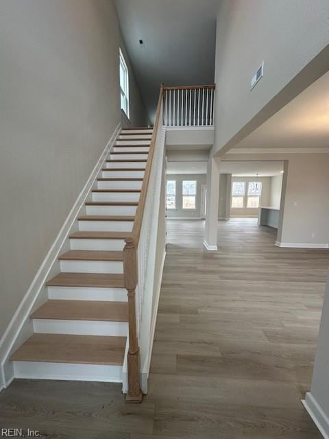 staircase with a high ceiling, wood finished floors, and baseboards