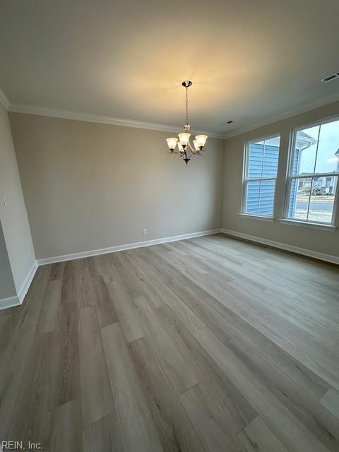 empty room featuring visible vents, baseboards, ornamental molding, and a chandelier