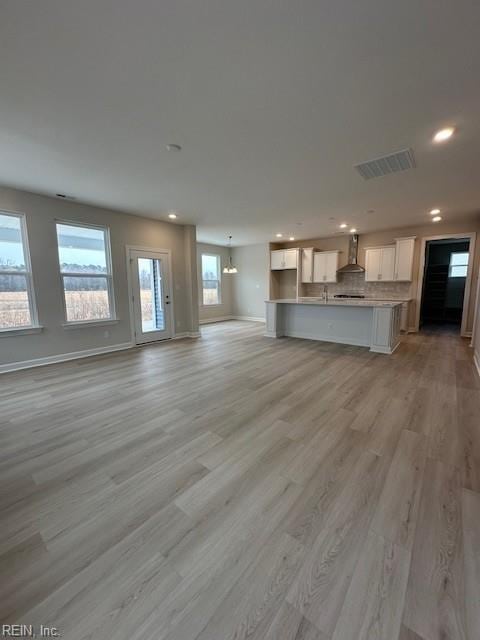 unfurnished living room with recessed lighting, visible vents, baseboards, and light wood-style flooring