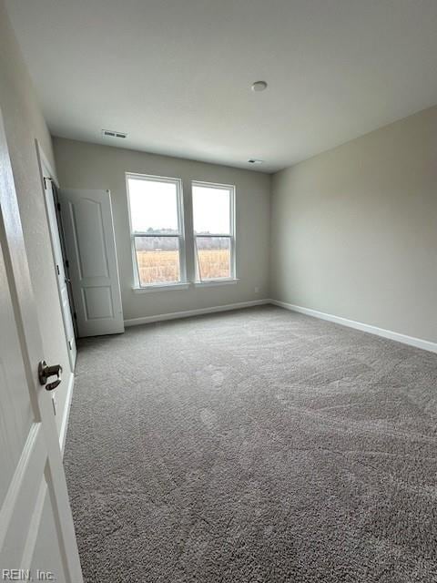 empty room featuring visible vents, baseboards, and carpet flooring