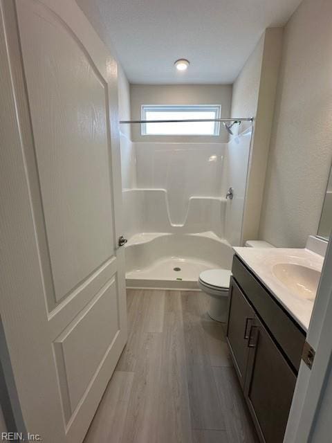 full bathroom featuring a shower, toilet, wood finished floors, and vanity