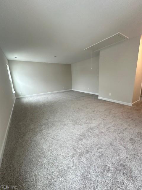 spare room with attic access, carpet, and baseboards