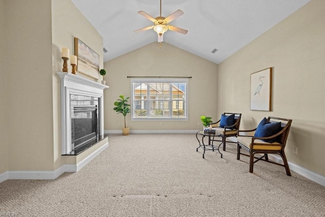 living area with baseboards, carpet, vaulted ceiling, a glass covered fireplace, and a ceiling fan