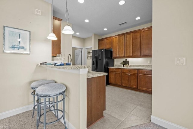 kitchen with a kitchen bar, a peninsula, recessed lighting, and brown cabinetry