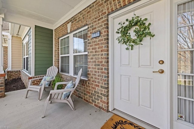 view of exterior entry featuring brick siding and a porch