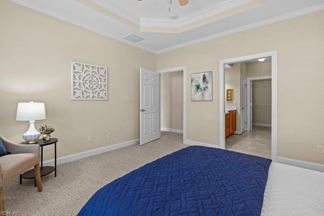 bedroom with visible vents, baseboards, a tray ceiling, ornamental molding, and connected bathroom