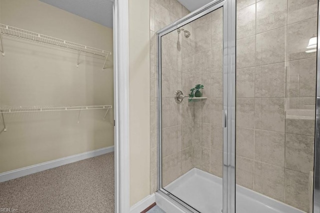 full bathroom featuring a walk in closet, baseboards, and a shower stall