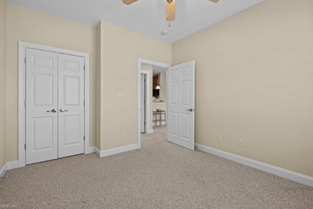 unfurnished bedroom with a closet, light colored carpet, and baseboards