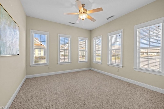 carpeted spare room with a wealth of natural light, visible vents, baseboards, and a ceiling fan