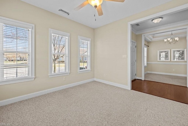 carpeted spare room with visible vents, baseboards, ornamental molding, and ceiling fan with notable chandelier