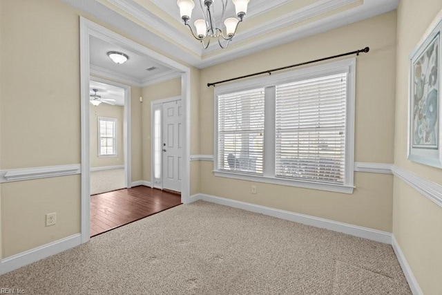 foyer entrance with carpet, baseboards, crown molding, a notable chandelier, and a raised ceiling