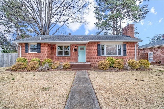 ranch-style home featuring a front yard, brick siding, a chimney, and fence