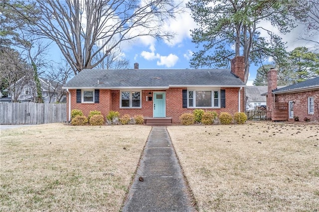 ranch-style house with brick siding, a chimney, a front yard, and fence