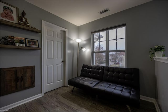 living area with visible vents, baseboards, and wood finished floors