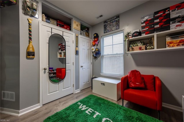 sitting room with visible vents, baseboards, and wood finished floors