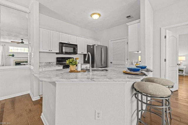 kitchen with wood finished floors, visible vents, ceiling fan, black appliances, and white cabinets