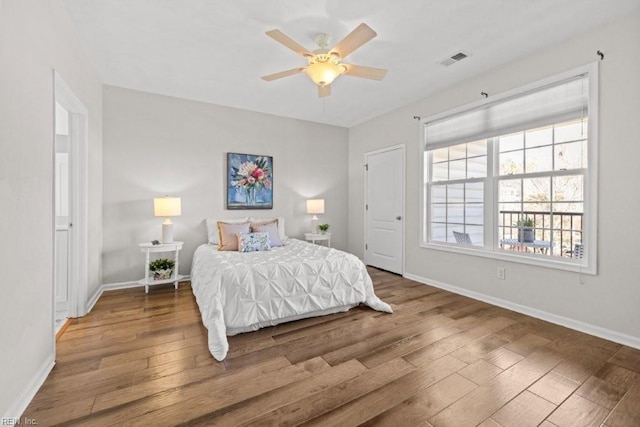 bedroom with ceiling fan, visible vents, baseboards, and wood finished floors