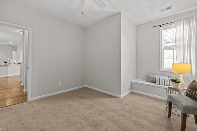 living area with baseboards, visible vents, carpet floors, and ceiling fan