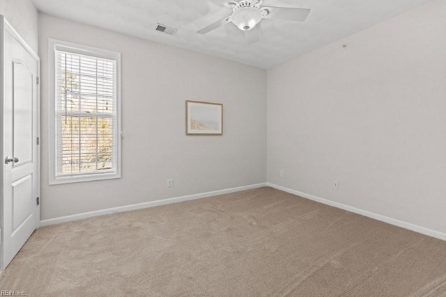 unfurnished room with baseboards, light colored carpet, visible vents, and ceiling fan