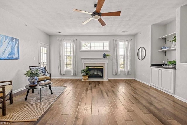 unfurnished living room with a healthy amount of sunlight, ceiling fan, and wood finished floors